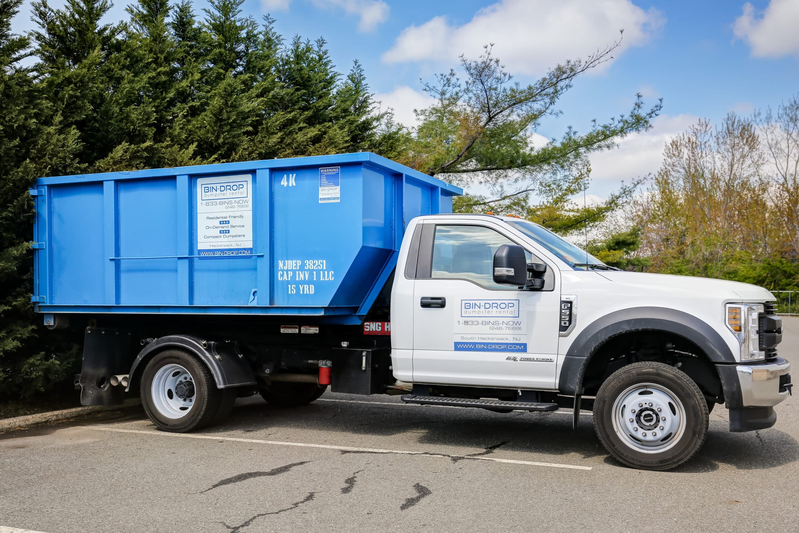 Bin-Drop truck delivering a concrete dumpster to a New Jersey job site